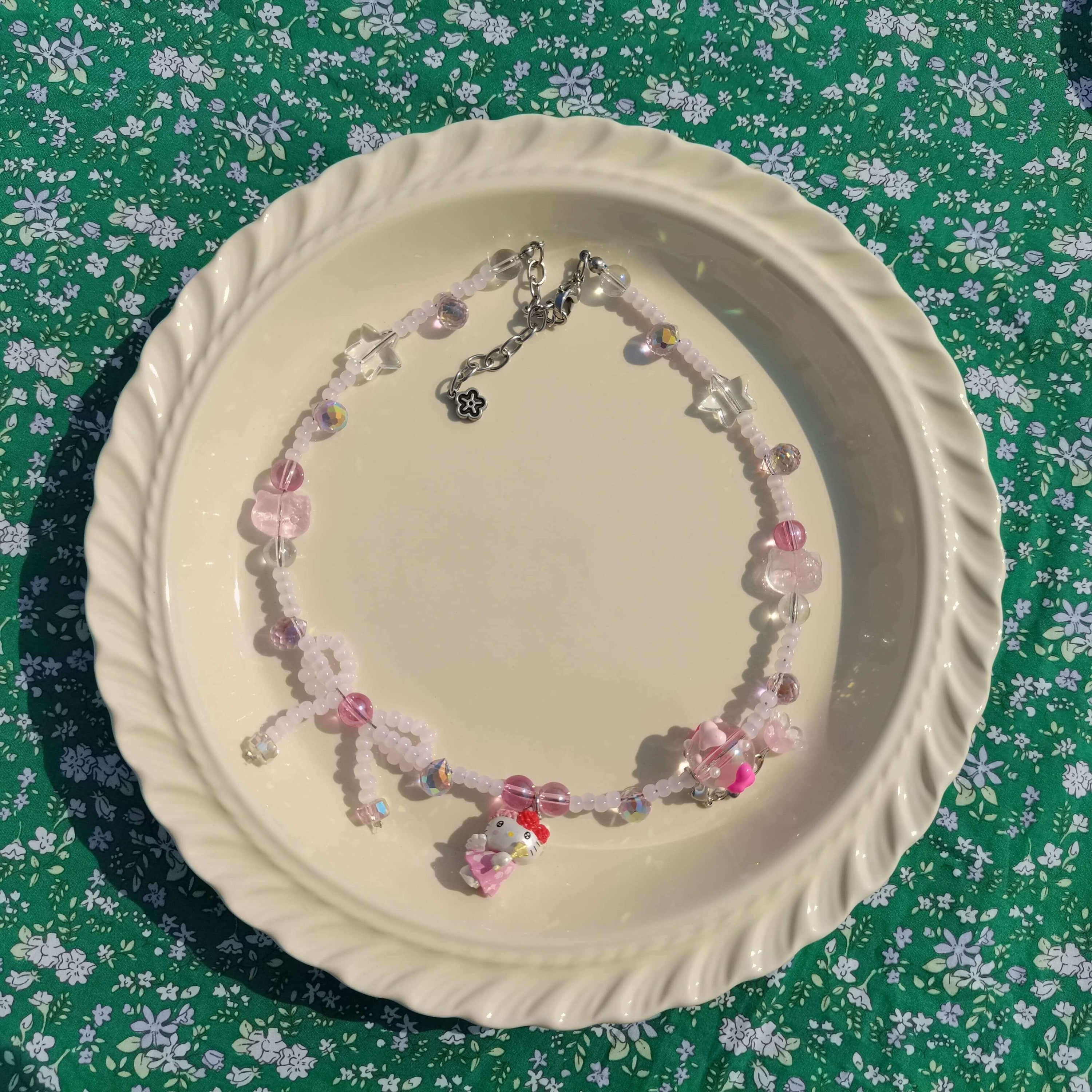 Artisanal Hello Kitty themed pink necklace displayed on a white dish