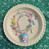 Artistic display of a Hello Kitty necklace surrounded by flower beads on a plate