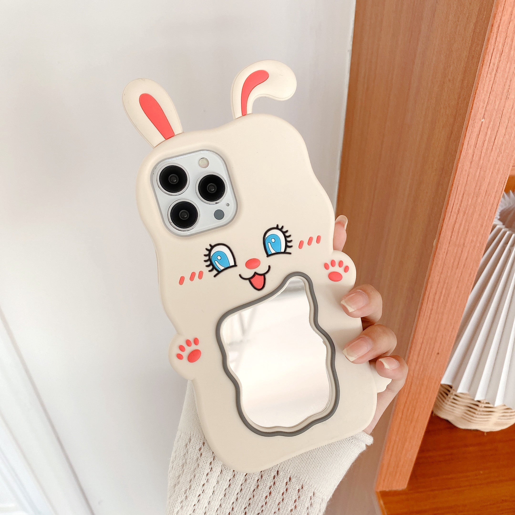 Close-up of a hand gripping an iPhone case with a whimsical rabbit character design