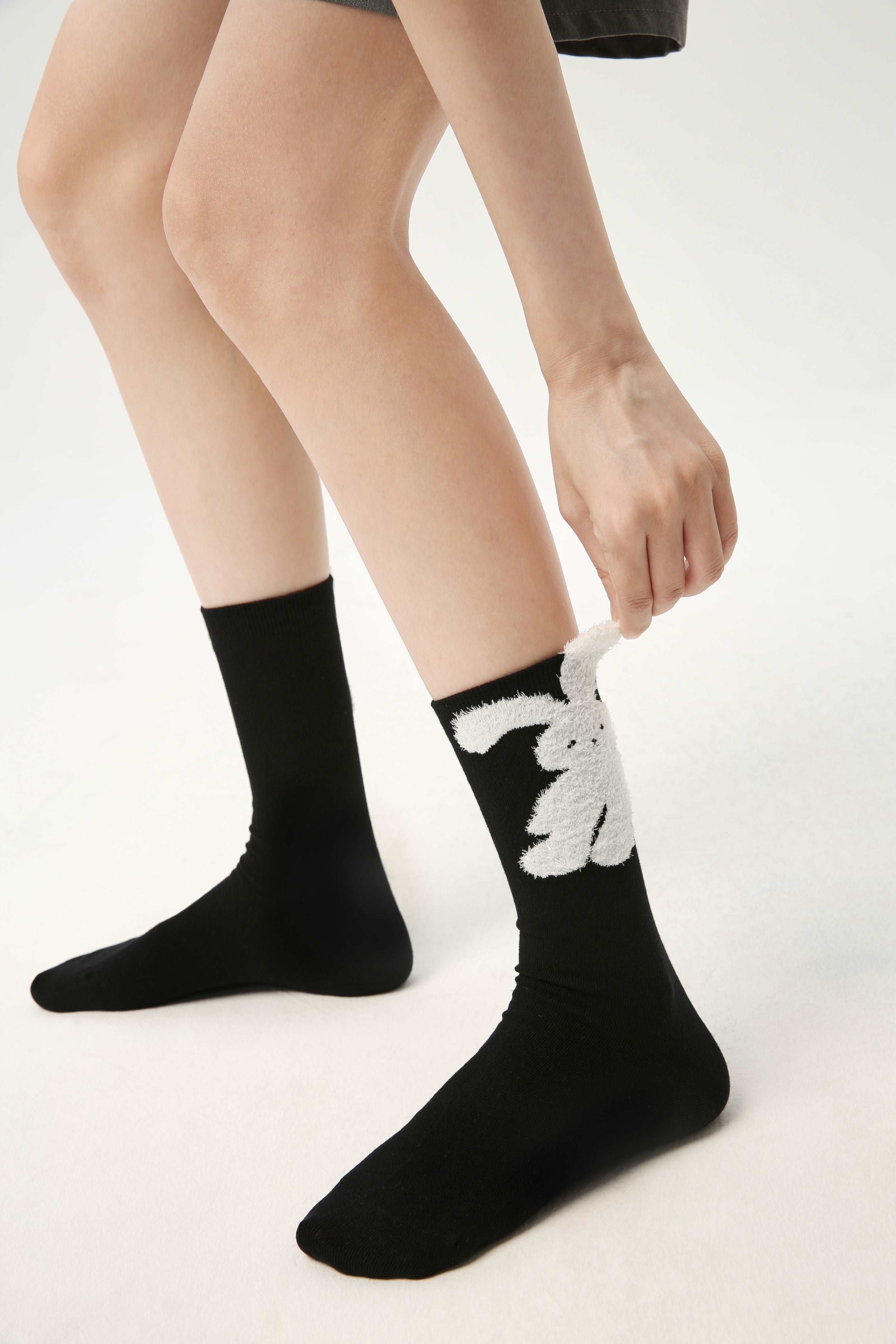 Woman pulling on a black sock from the Y2K-inspired women's fashion sock set