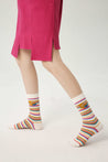 A model showcasing a set of 3+2 multicolored socks including black, white, green, yellow, and rainbow patterns