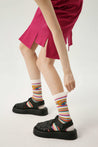 Woman in a pink outfit paired with green and yellow striped socks from the set