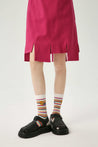 Girl in a pink skirt complementing her outfit with yellow and green striped socks