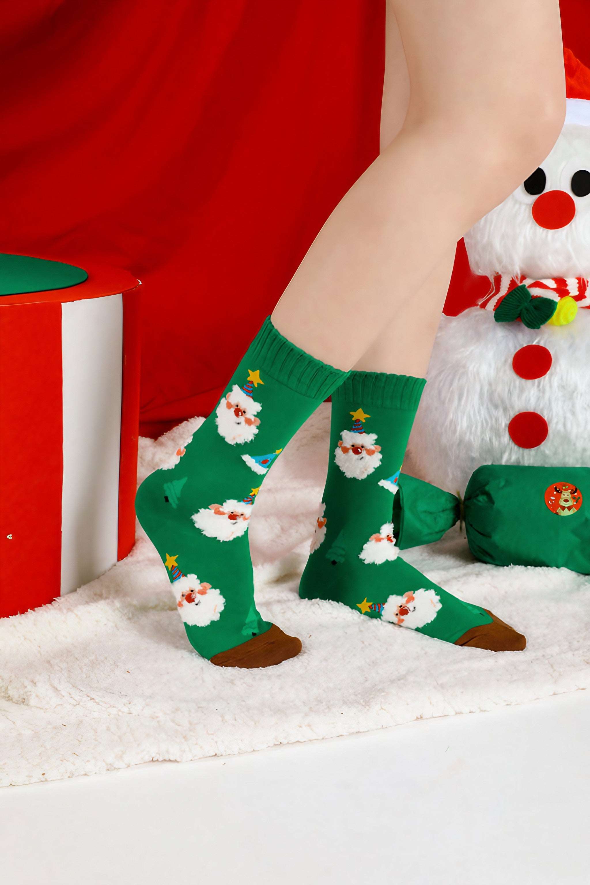 Green holiday socks with a Santa Claus design worn by a woman