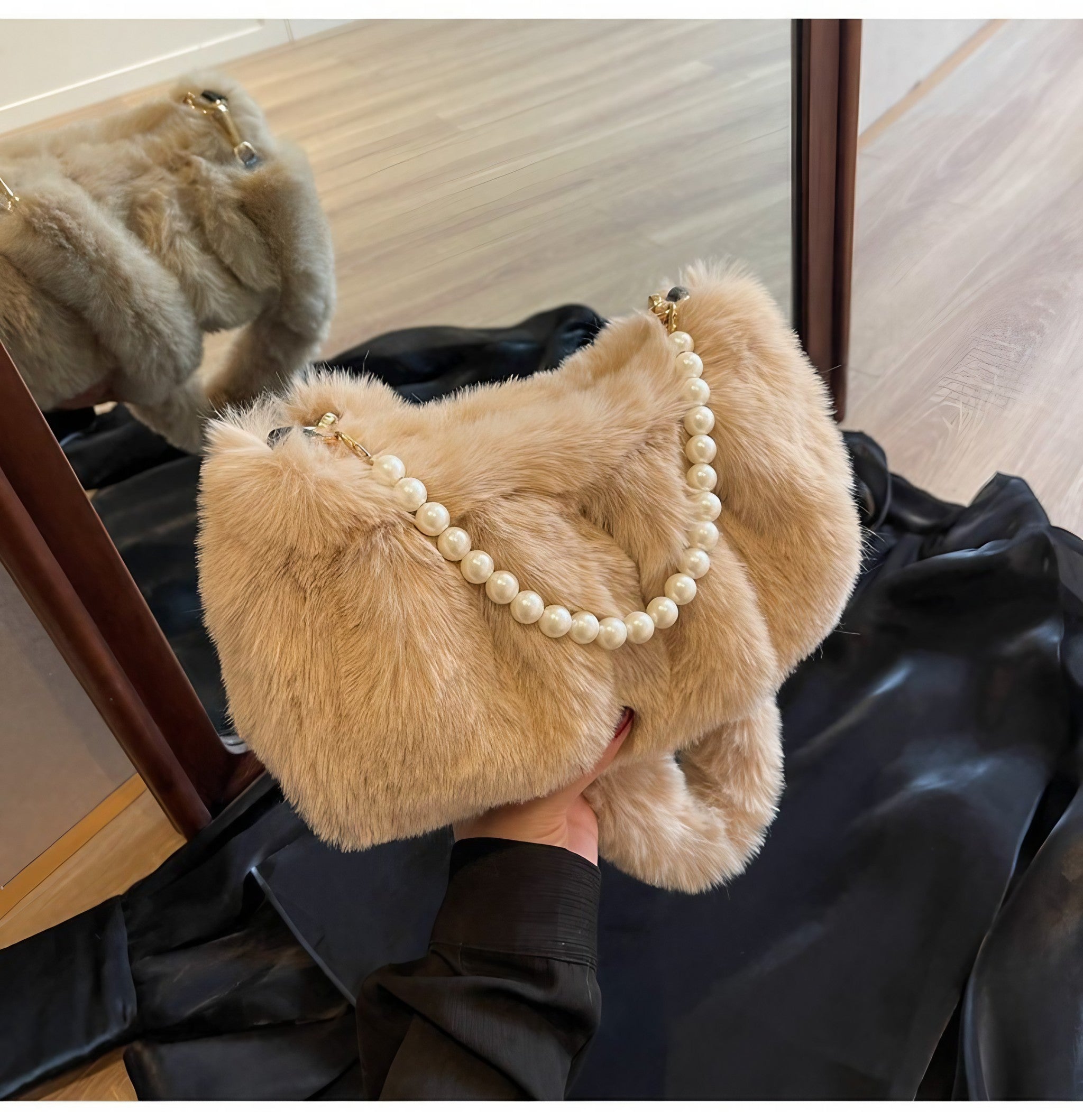 Detail shot of a woman's hand holding a brown plush fur bag with pearl details