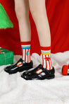 Close-up of a woman's feet in stylish black shoes and festive tree-patterned socks