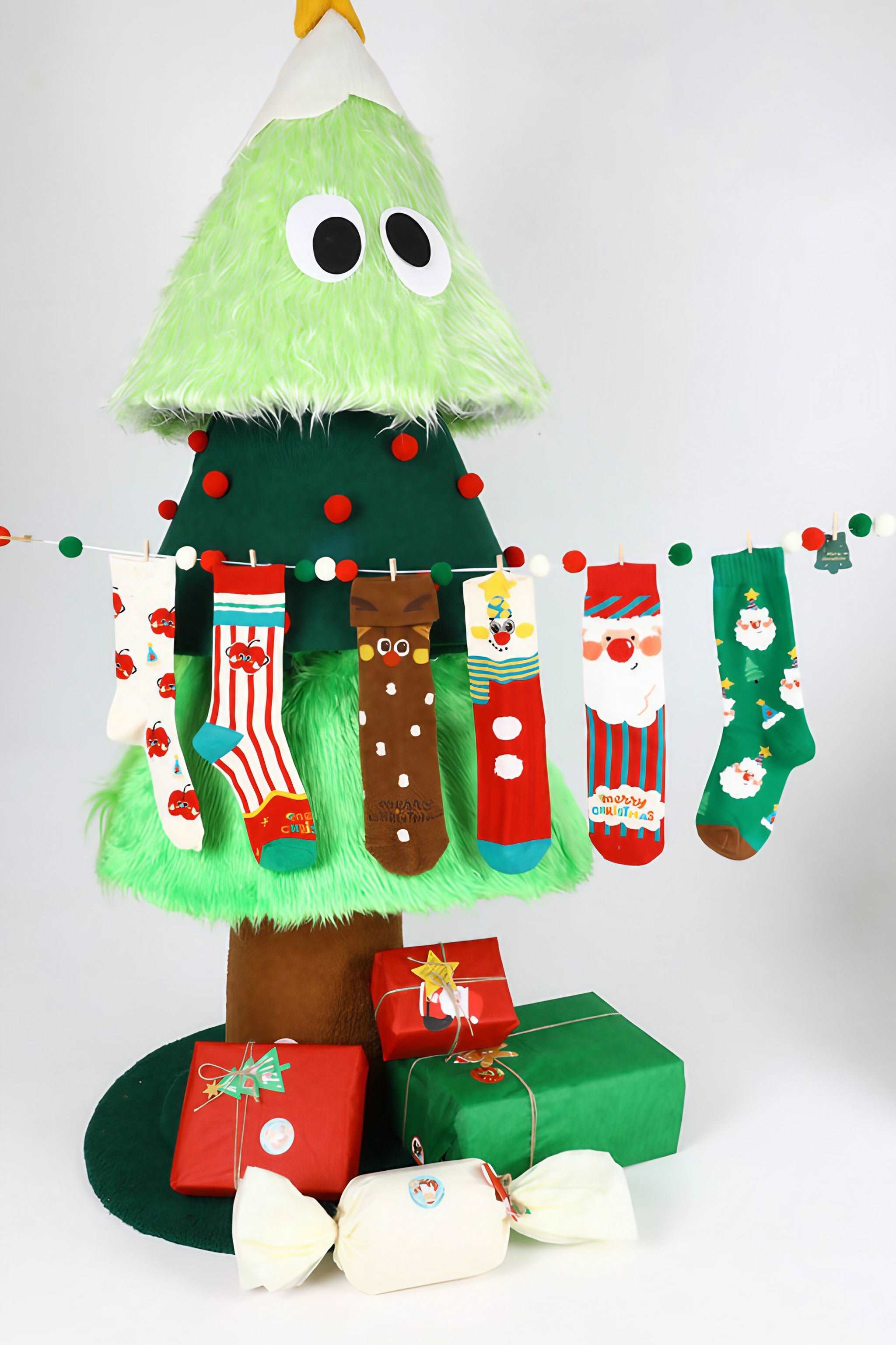 Decorated Christmas tree surrounded by wrapped gifts and festive socks collection