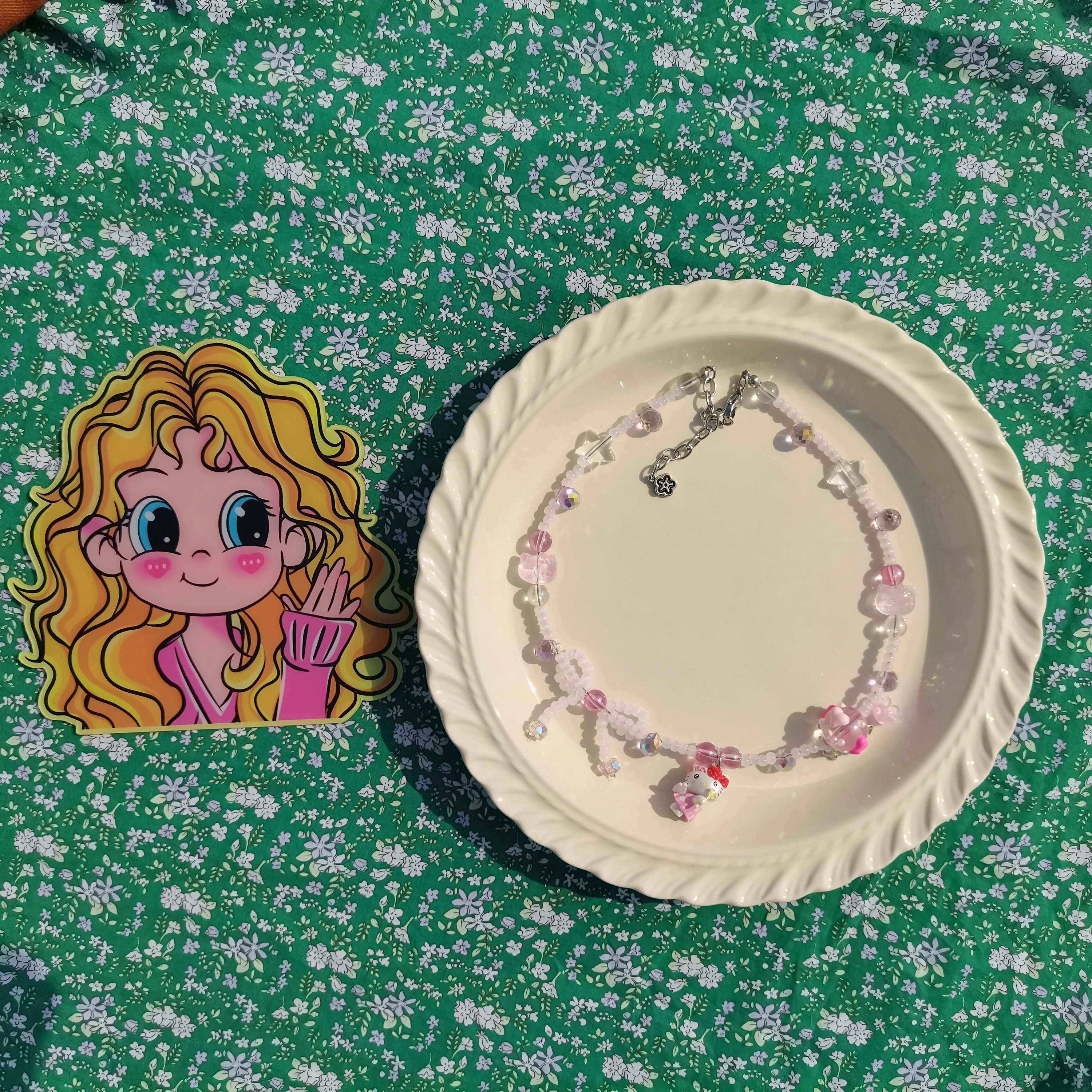 Hello Kitty inspired necklace with pink beads presented on a plate