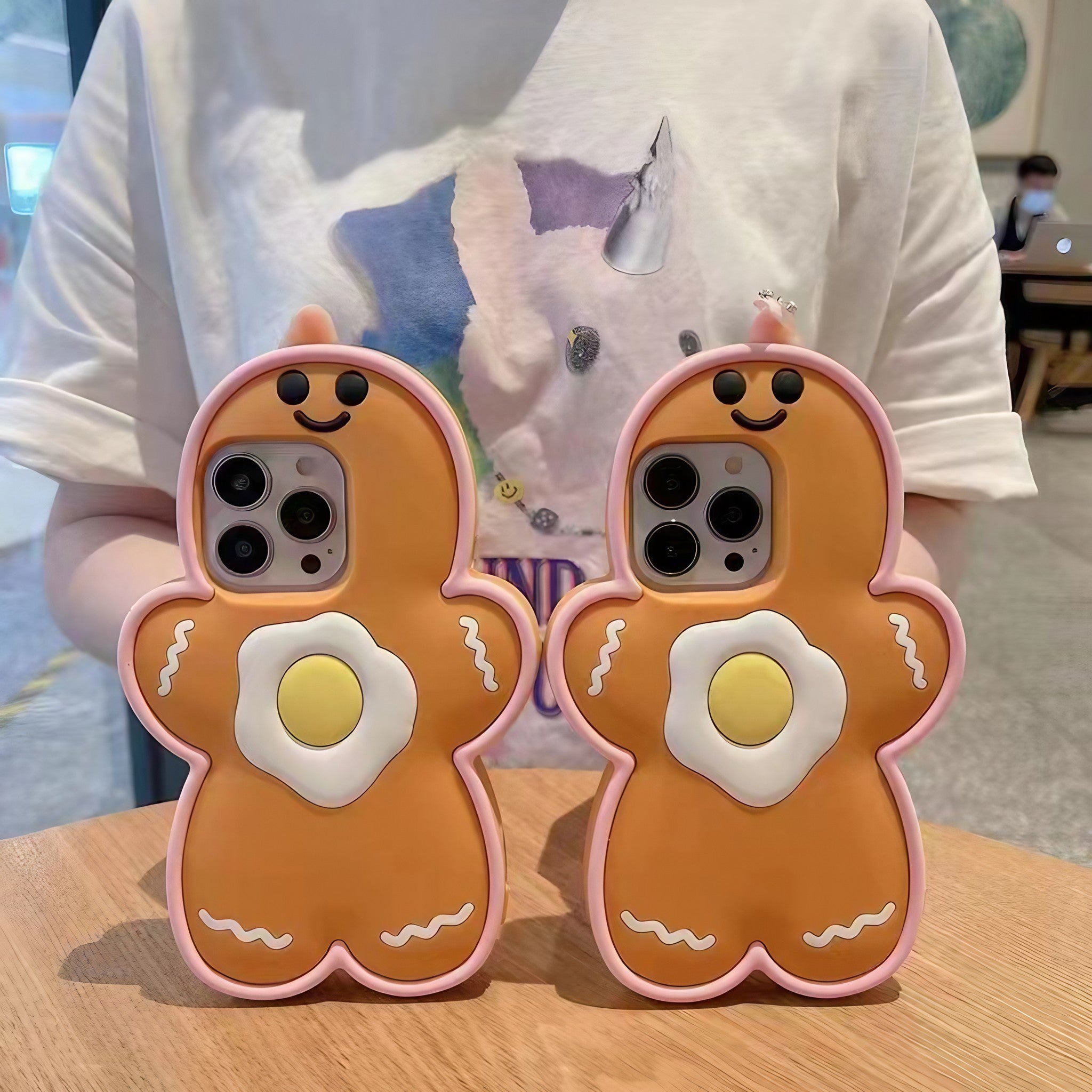 A pair of iPhone cases featuring gingerbread man and egg designs for the holiday season