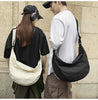 A couple standing side by side, one with a white canvas bag and the other with black one