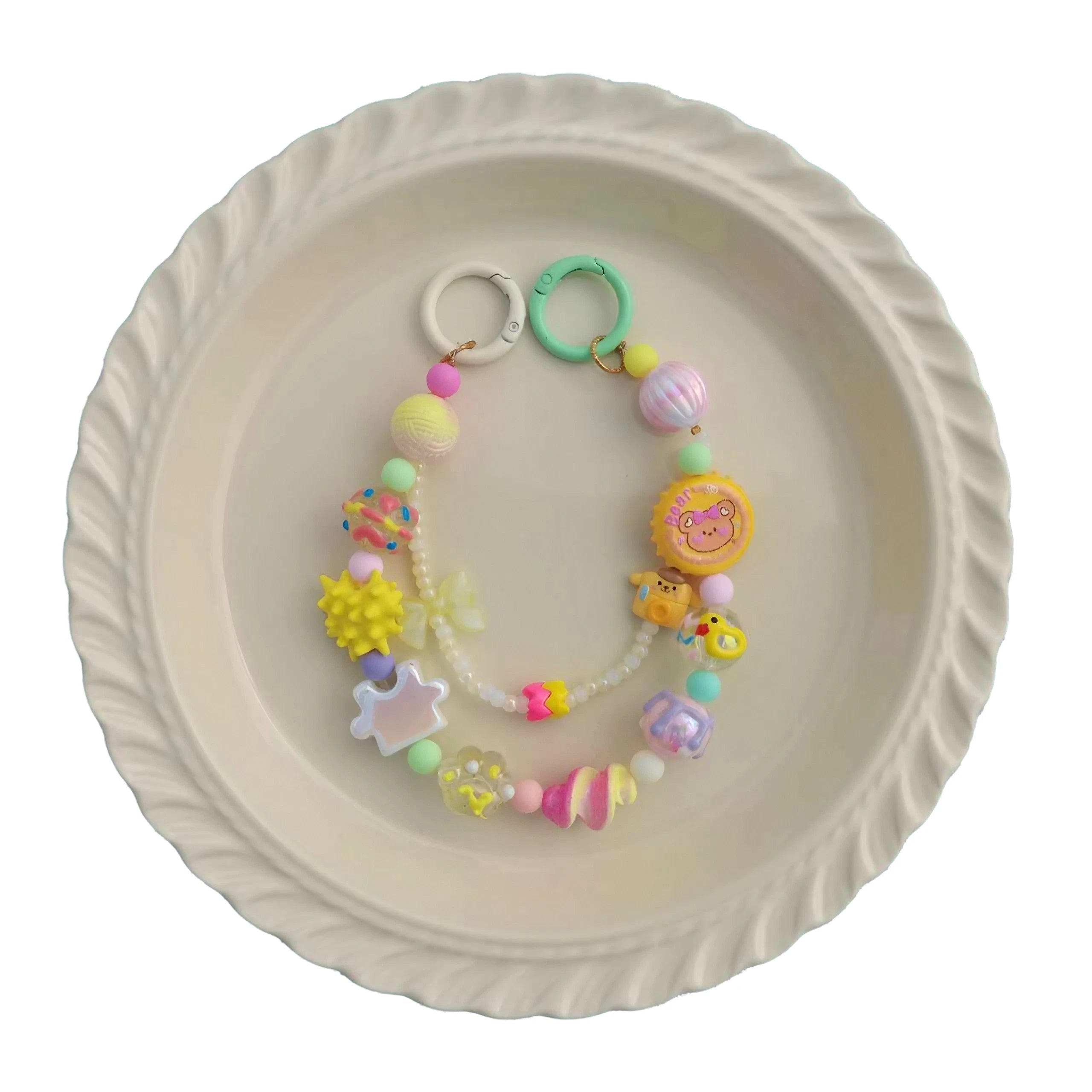 A pastel-colored handbag chain with plastic beads arranged on a white plate
