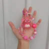 A hand displaying the Coquette Fashion Essential pink bag chain with pink beads