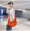 Person in a hat stylishly carrying a funky orange canvas bag