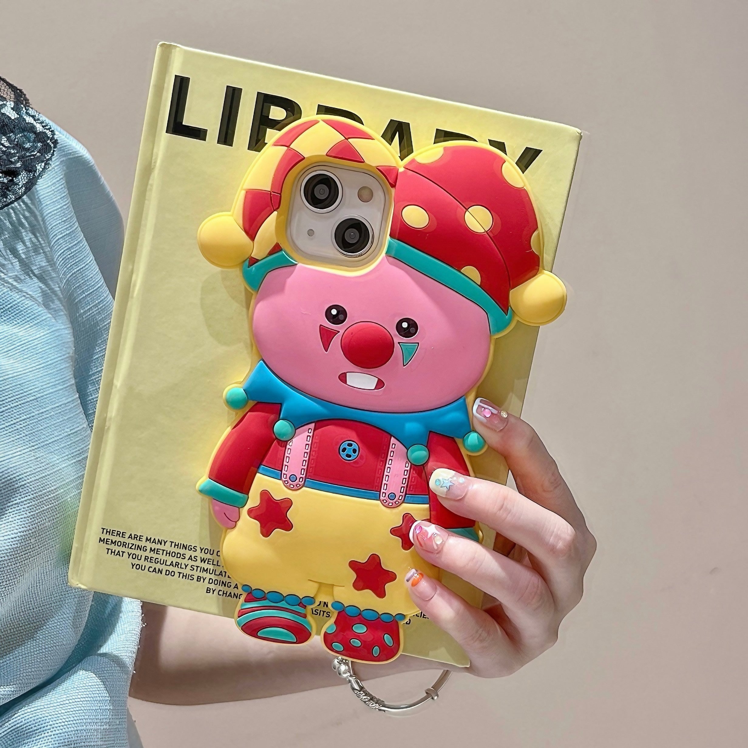 A woman displaying a pink Loopy Pierrot iPhone case with a jester graphic for iPhone 13 Pro Max