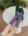 Woman's feet in purple socks complemented by green footwear