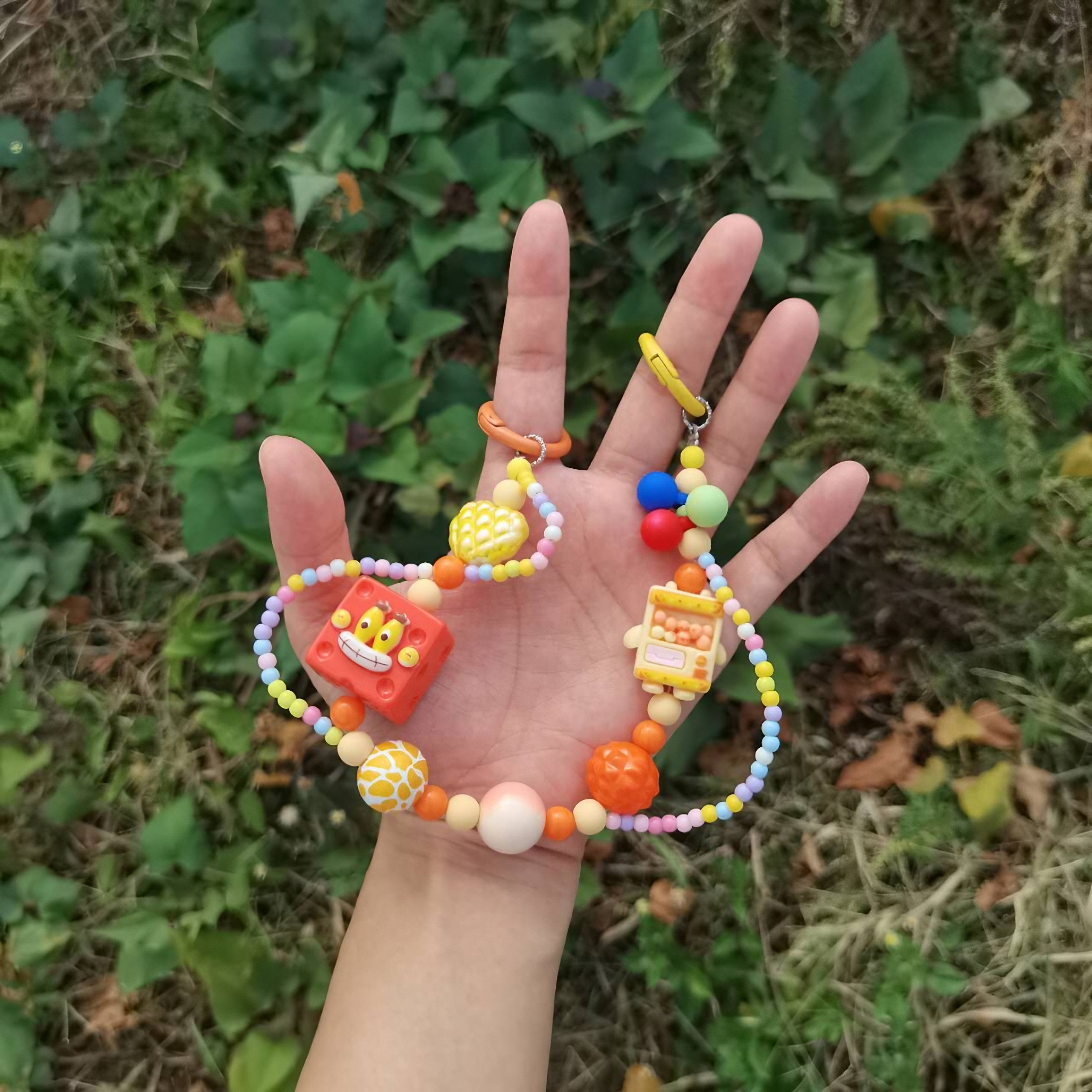 A person holding a SpongeBob keychain with yellow and orange beads