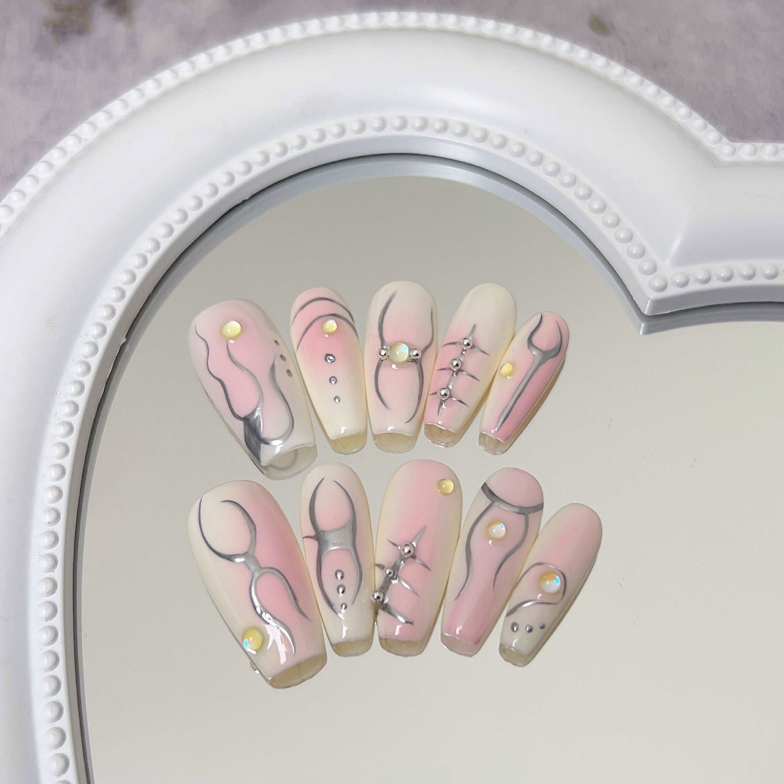 Close-up of Ballet Coquette pink and white nail designs on a reflective background