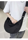 Model casually carrying a black canvas gym bag over their shoulder