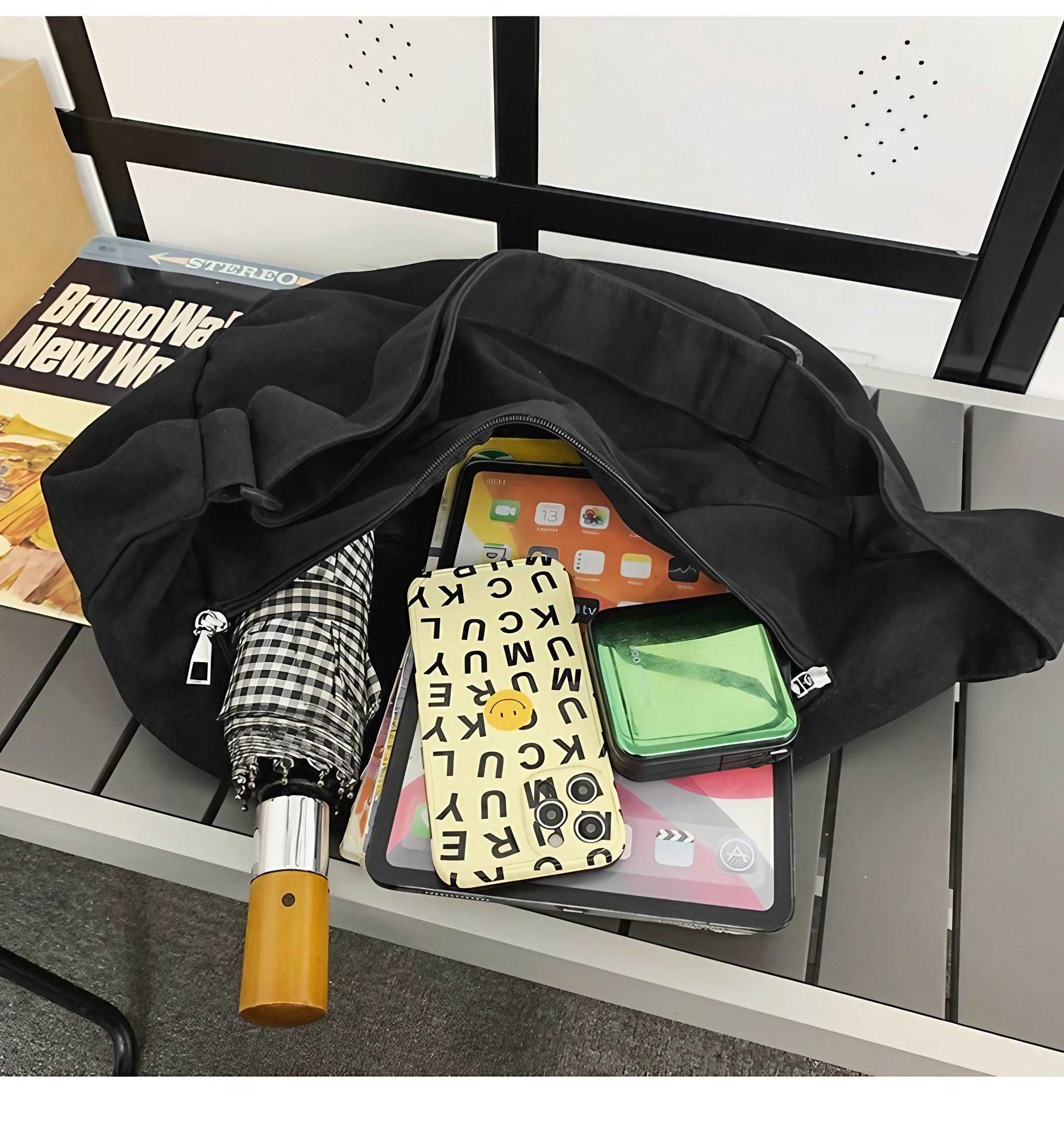 Black canvas bag accompanied by essentials like a phone, iPad and umbrella for a day out