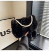 Elegant black plush fur bag with pearl embellishments held by a woman