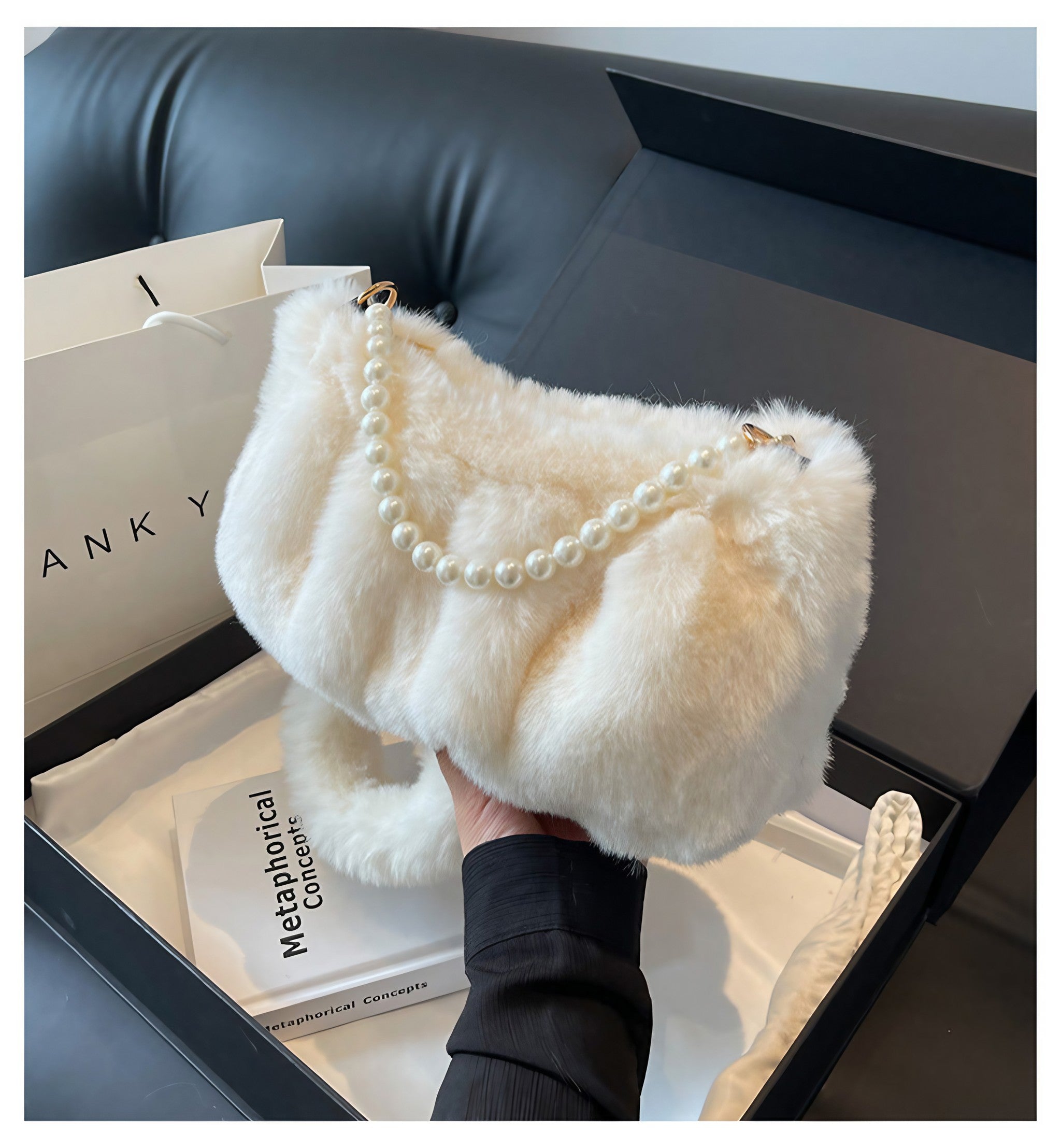 Woman's hand elegantly displaying a white plush fur purse