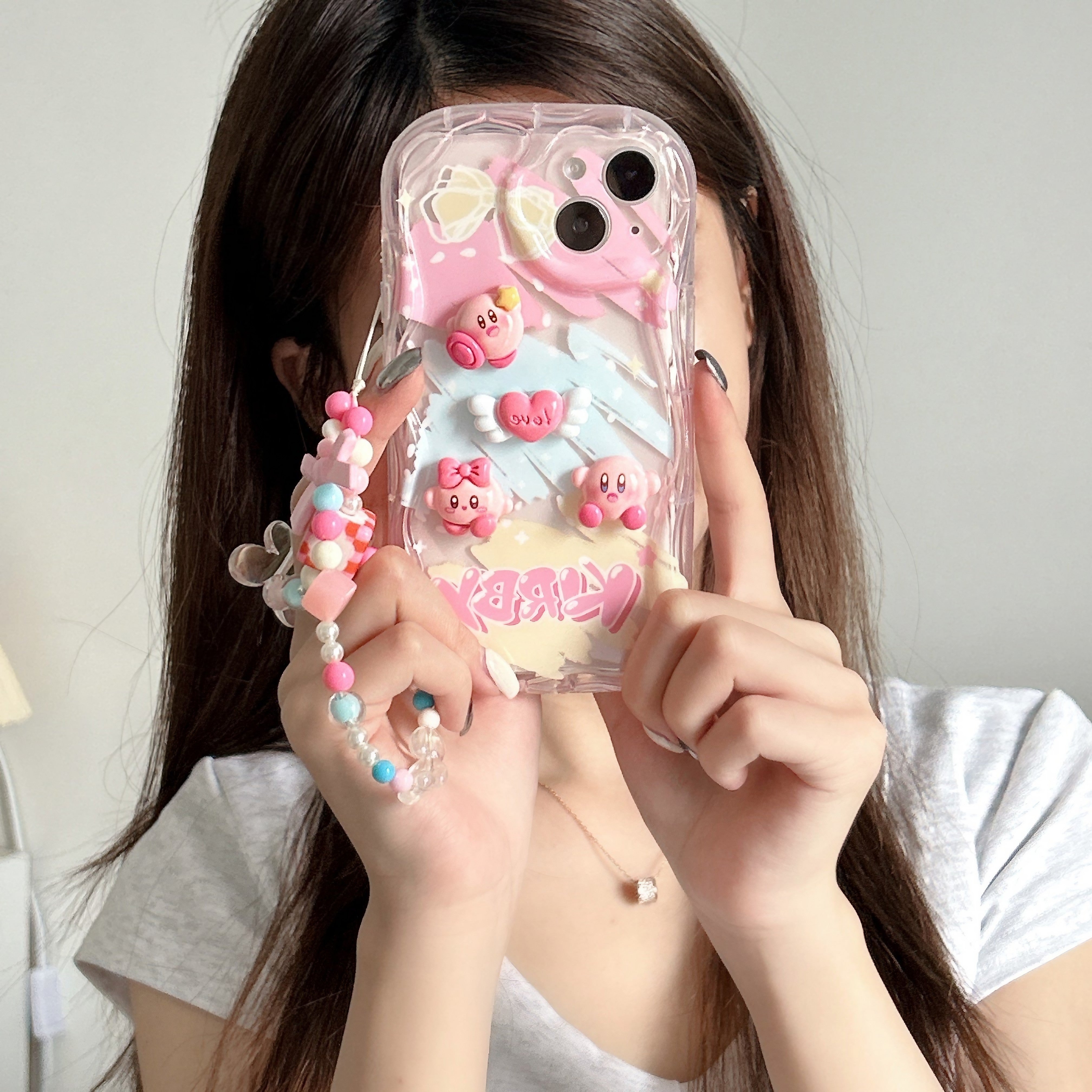 Person displaying a Kirby character iPhone case with a soft pink color scheme for iPhone 14 Pro