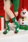 Woman's feet in vibrant green holiday socks matching her green Santa-themed sweater