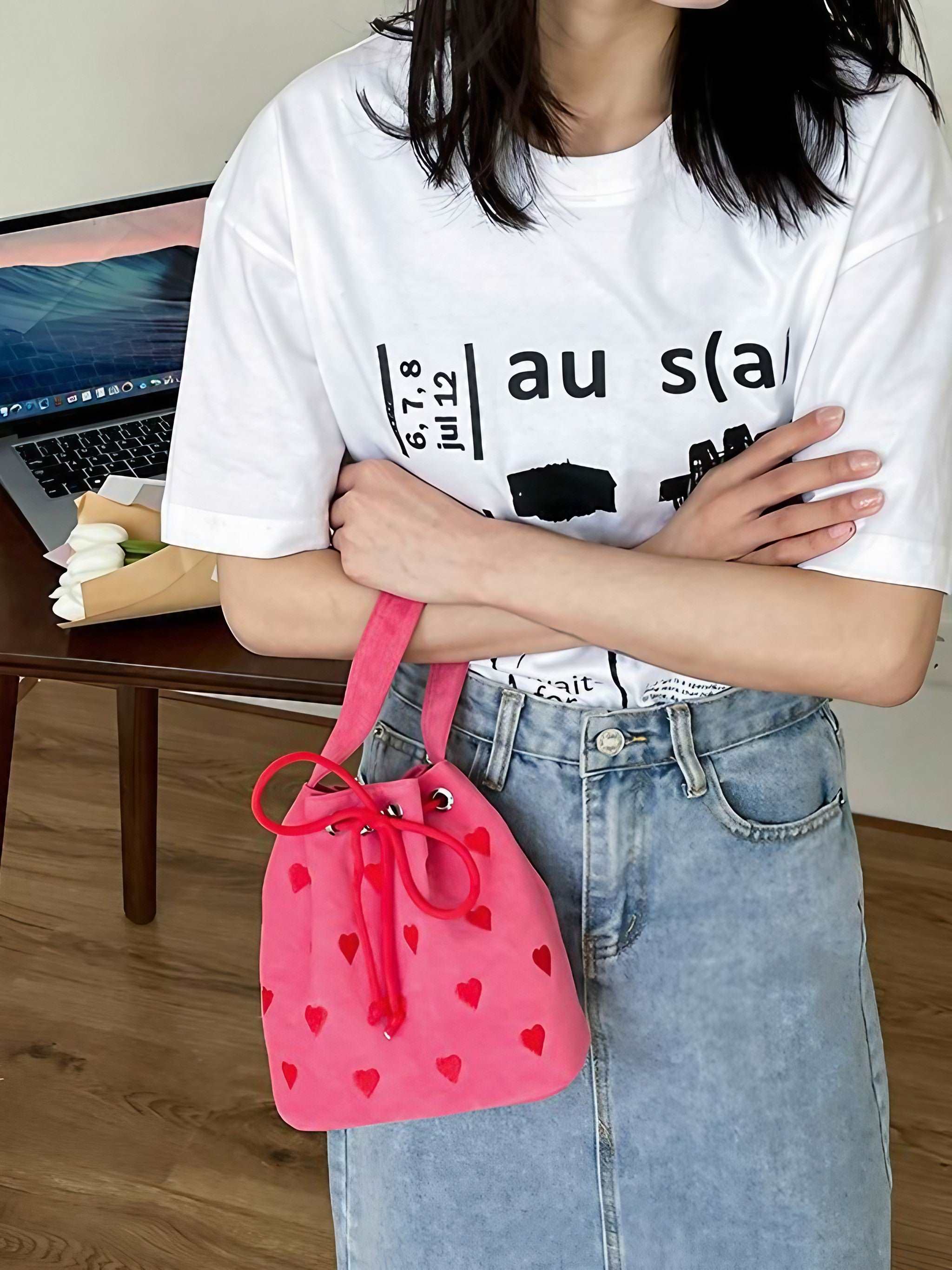 A woman dressed in a white top carrying a pink heart-shaped shoulder bag