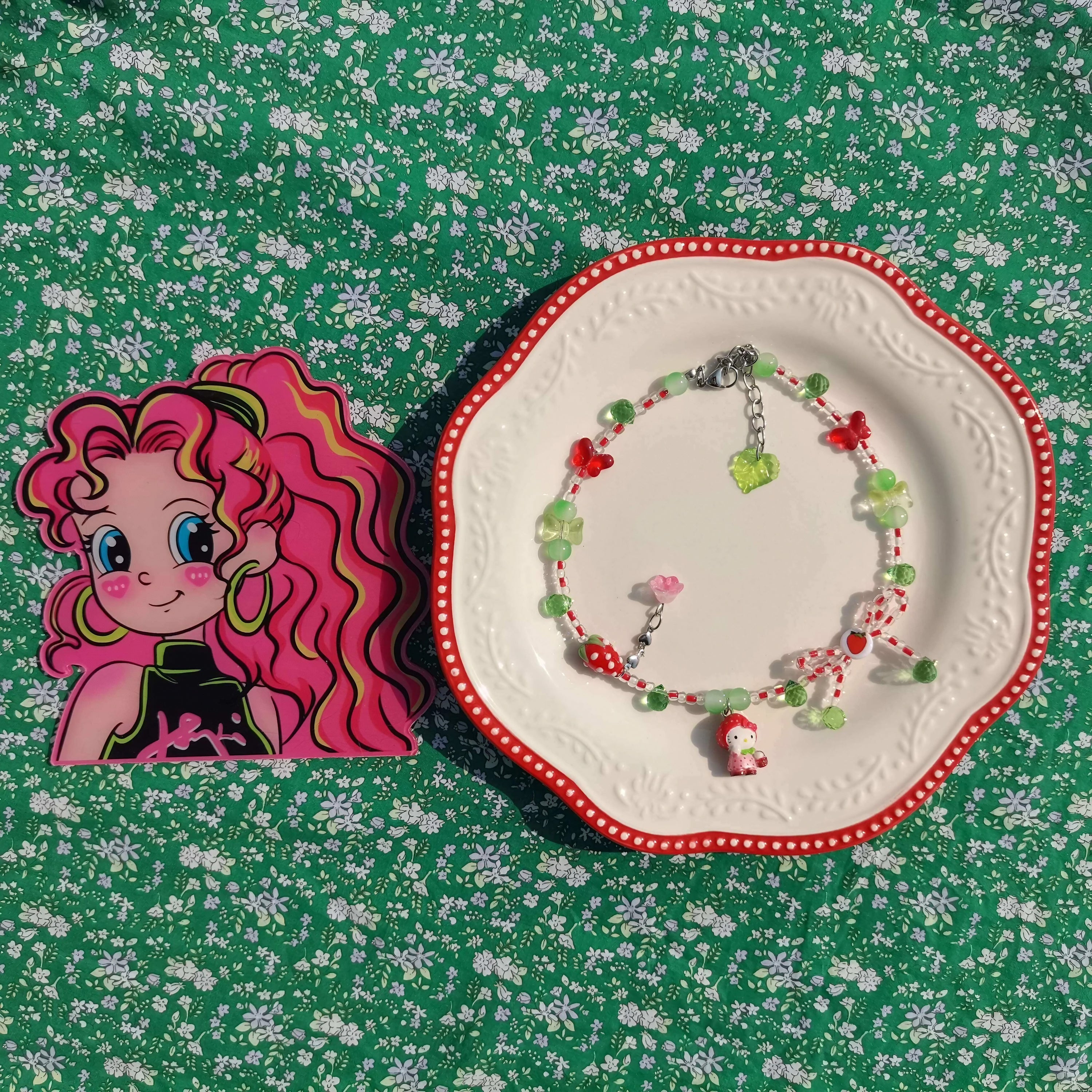 A decorative red Hello Kitty necklace presented on a plate