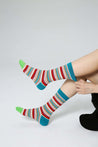 Woman lounging in striped Blackpink socks against a pristine white backdrop