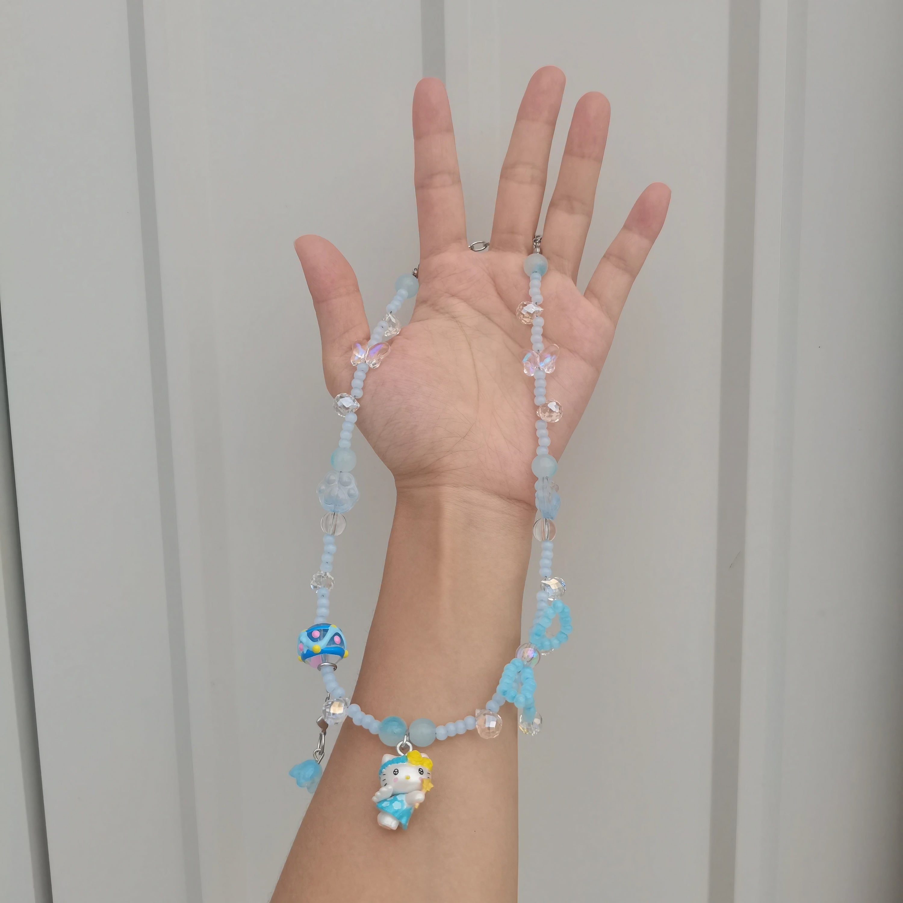 A person displaying a handmade beaded Hello Kitty necklace in Y2K style