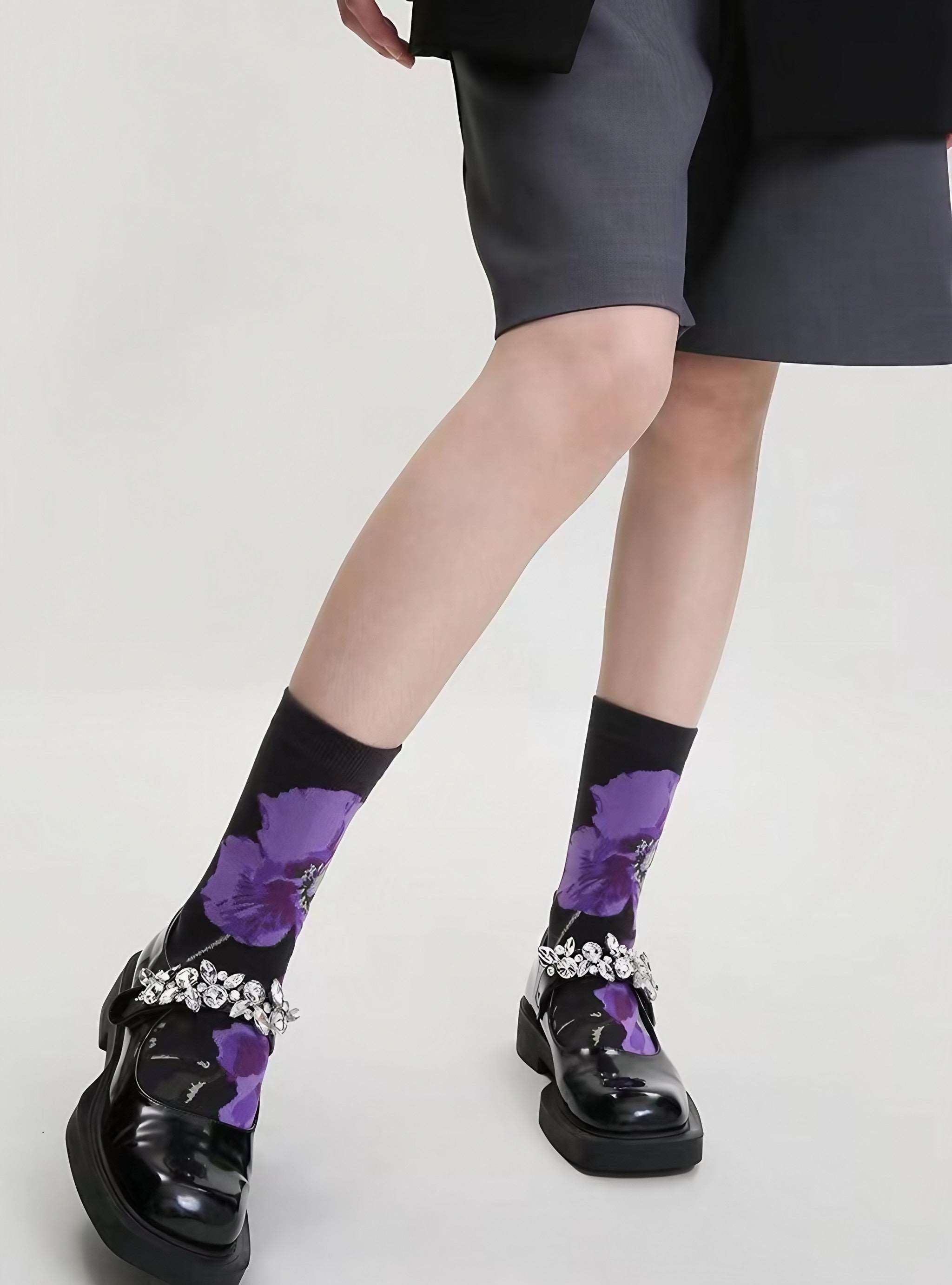 Purple and black socks with floral detailing worn by a woman