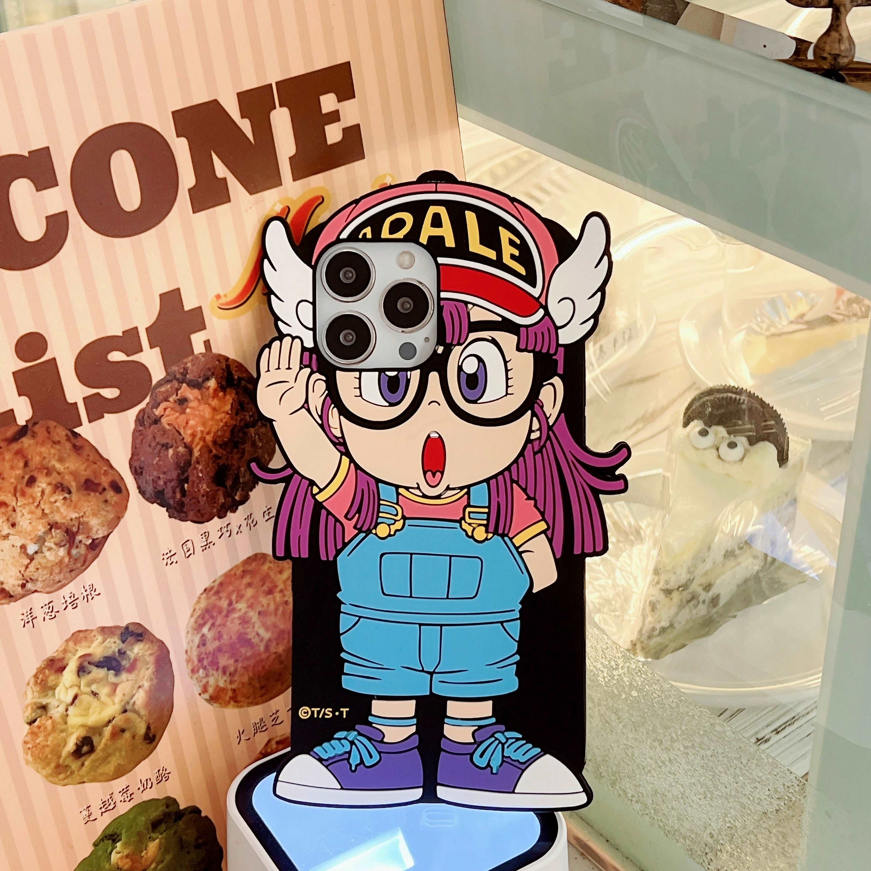 Arale from Dr. Slump character on a shockproof iPhone case in front of a bakery setting