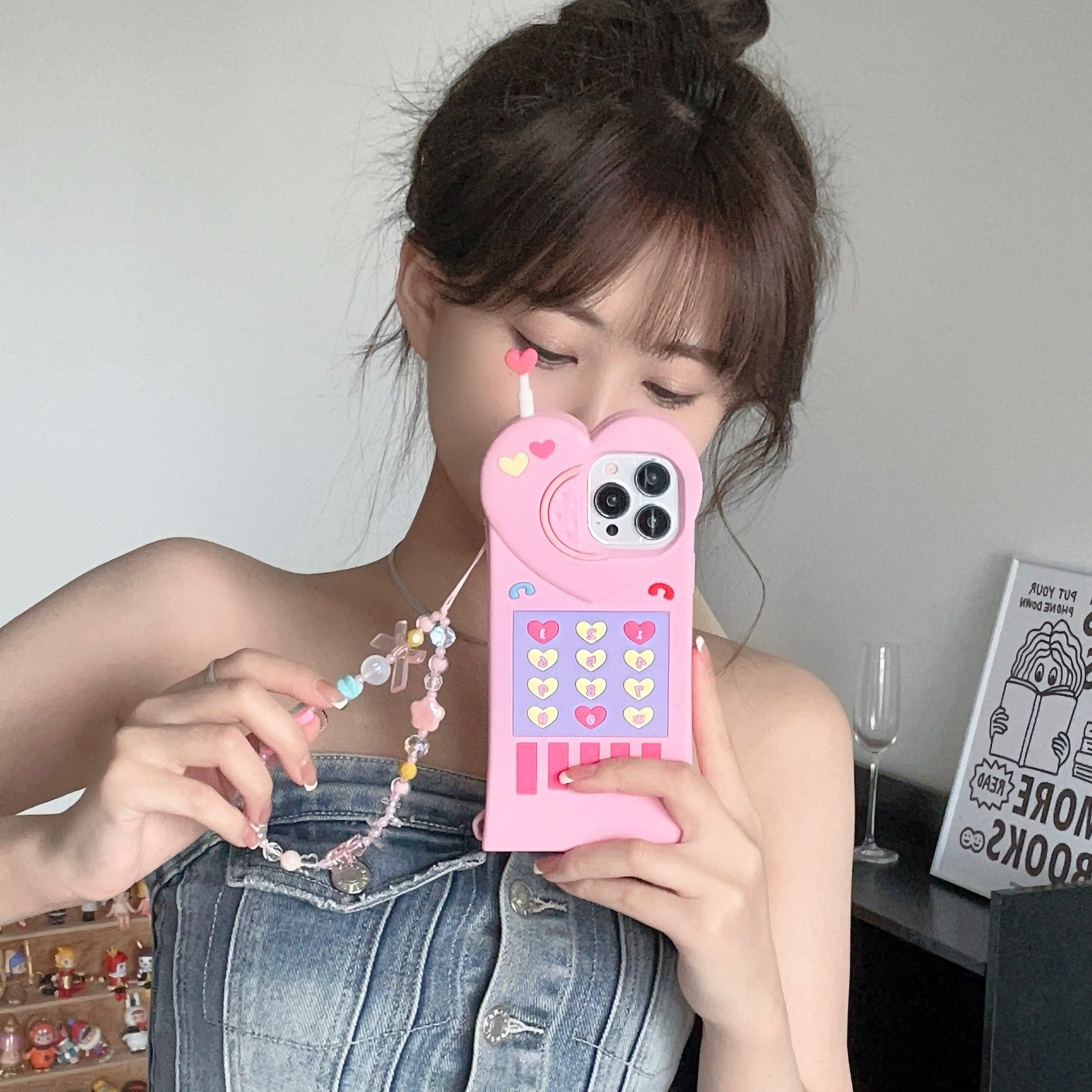 Close-up of a woman's hand holding a pink iPhone case with a heart decoration