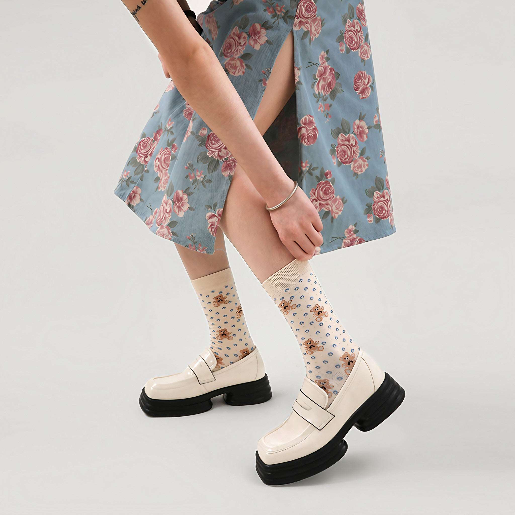 Side view of a woman wearing a pair of beige bear socks with a floral denim skirt