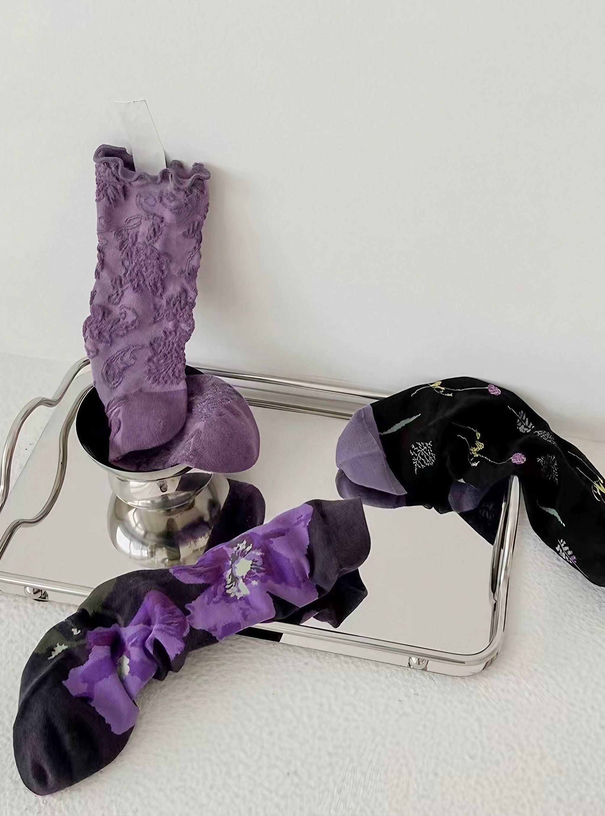 Trio of purple-hued socks presented on a metallic silver tray