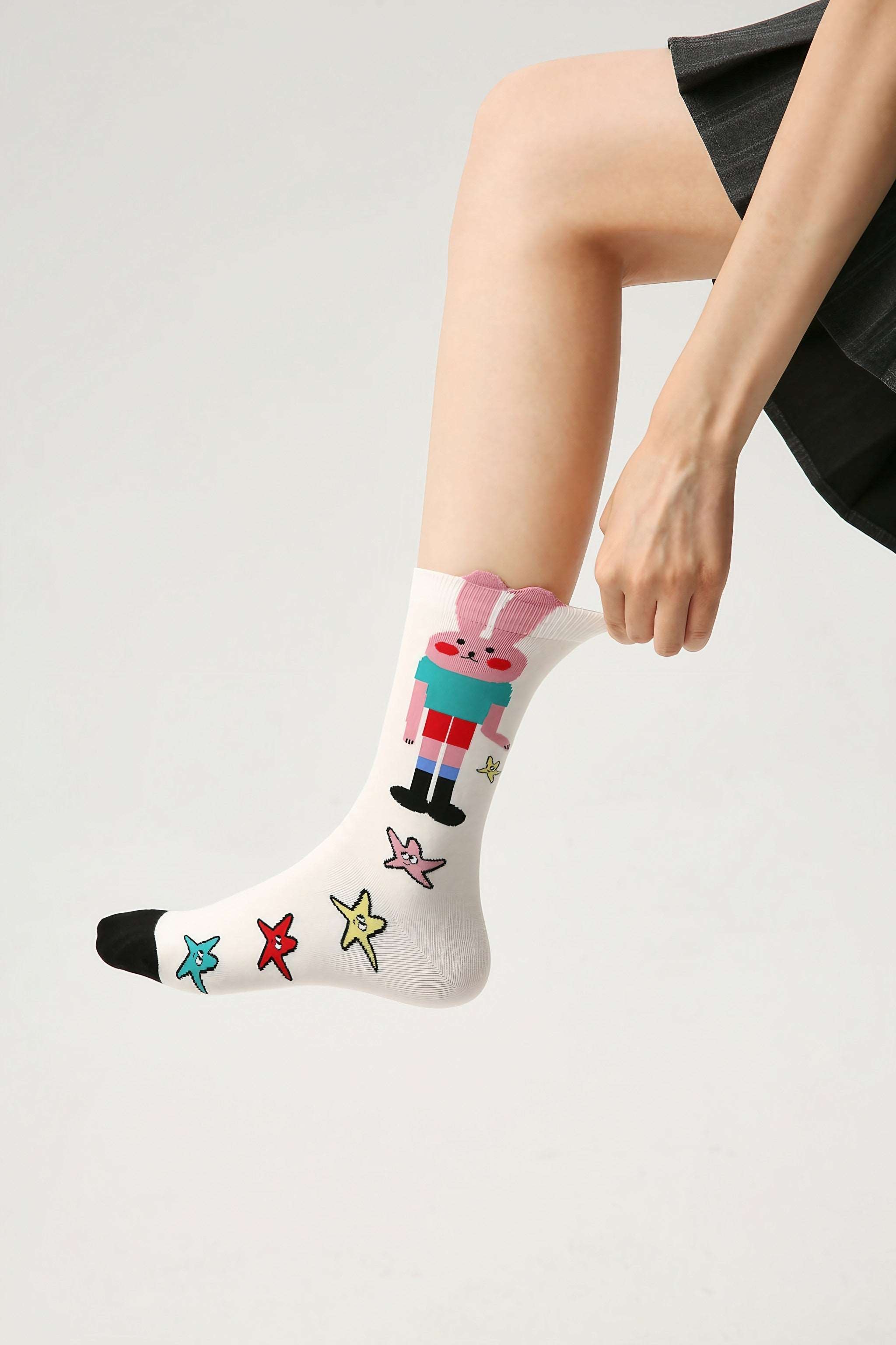 A woman showcasing a pair of rabbit-themed socks from the 3+2 set