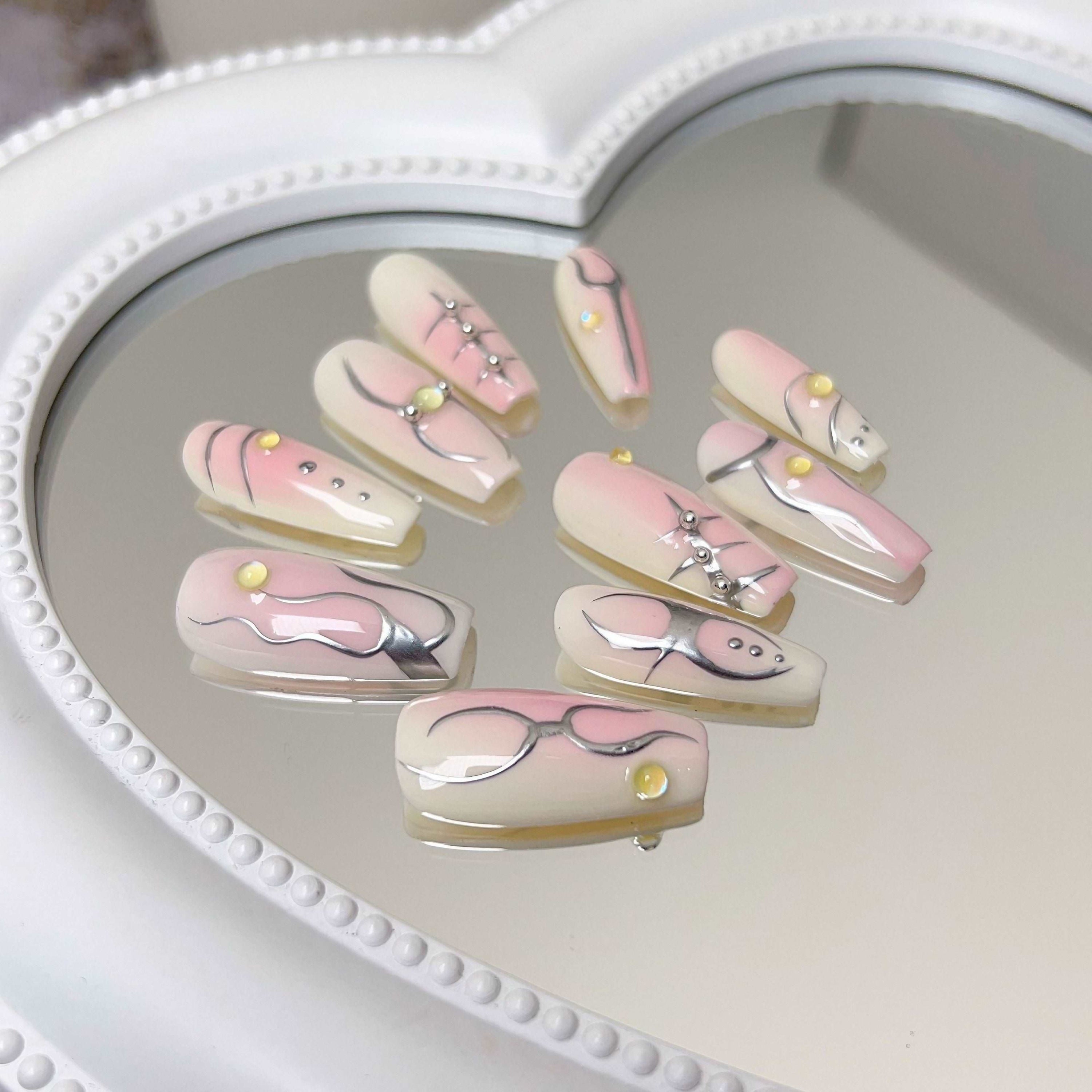 Assorted Ballet Coquette false nails arranged on a mirror