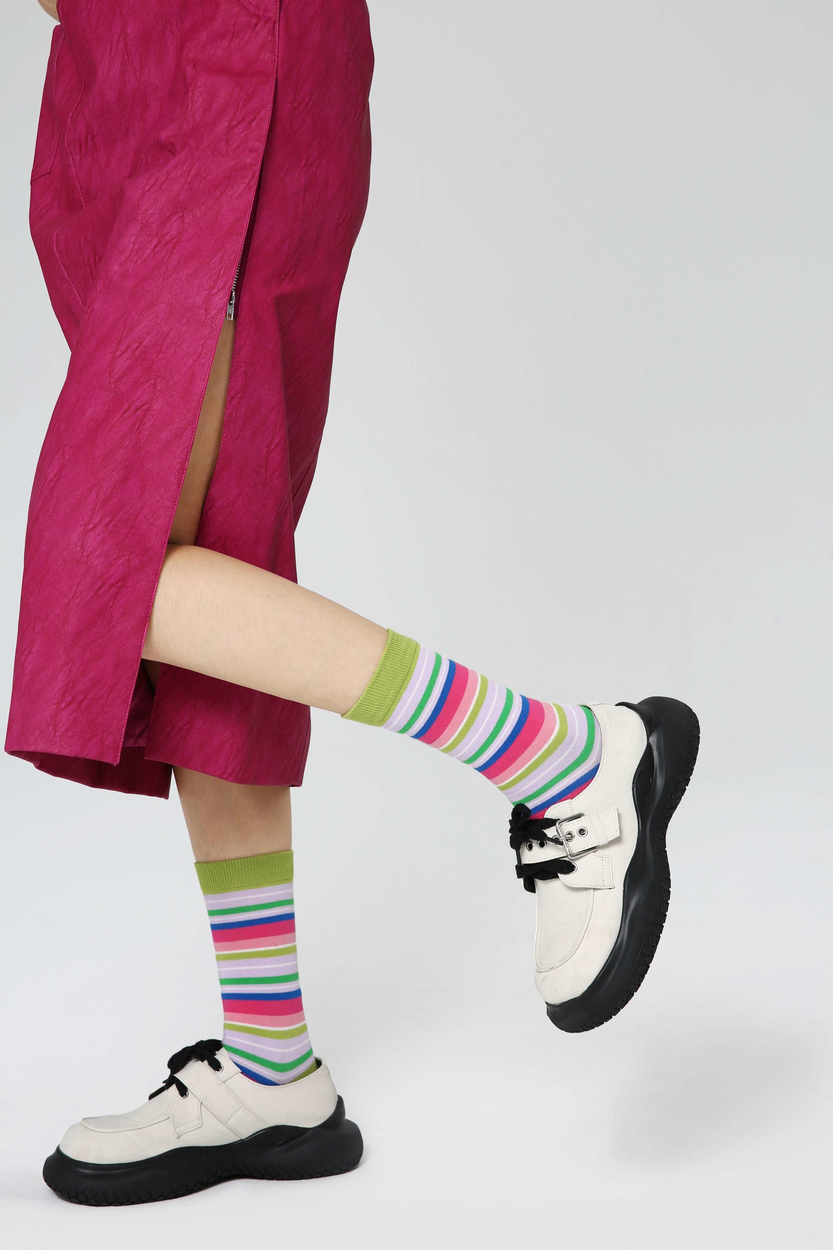 Woman's feet adorned with multicolored socks complementing her pink skirt