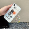 A person gripping an iPhone case that features a coconut tree image and comes with a trendy phone chain