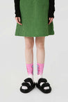 Pink socks from the set, styled with a green skirt for a pop of color