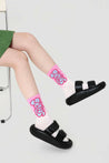 Female feet adorned with pink socks from the set, paired with black sandals