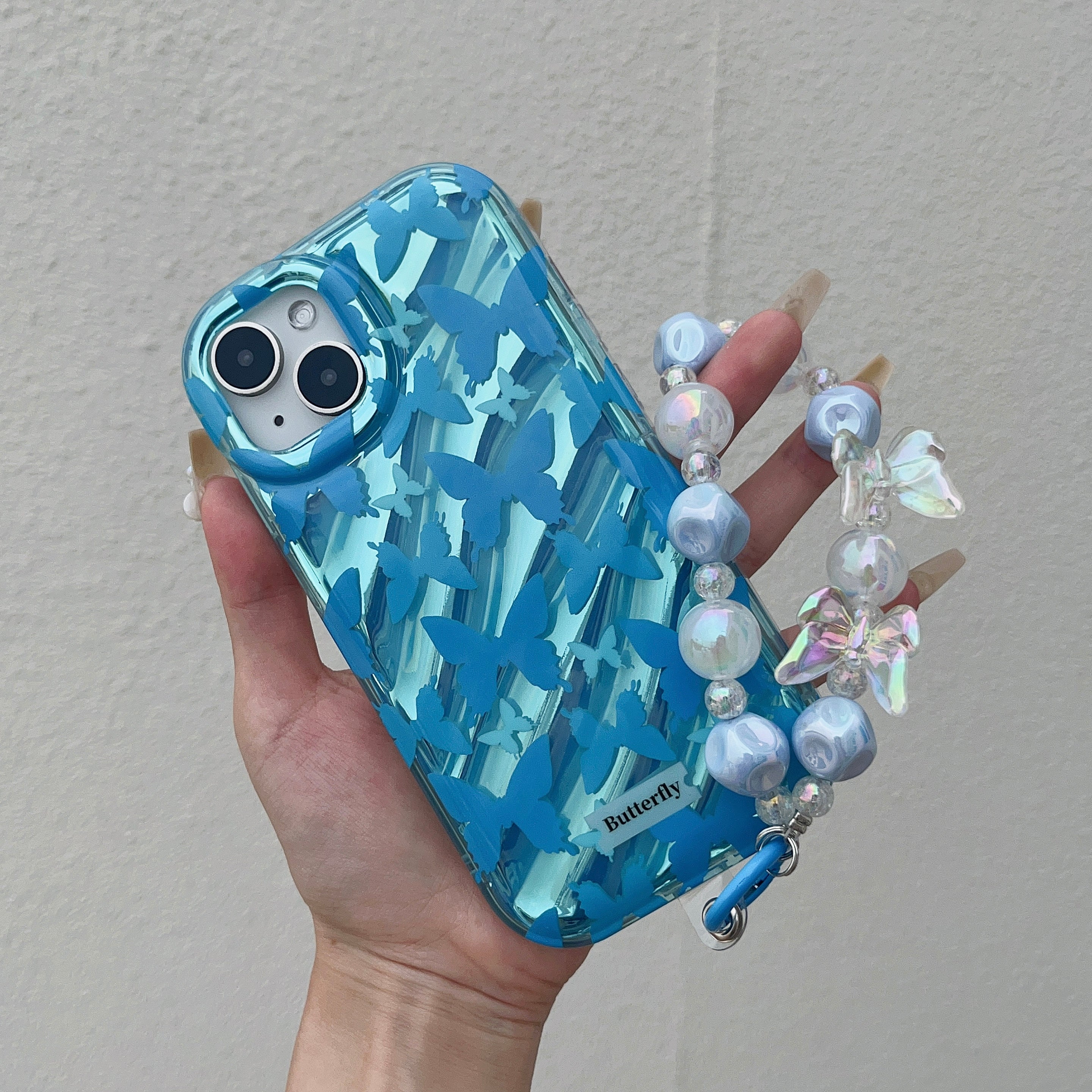 An individual presenting an iPhone case adorned with blue and white beads for the iPhone 14 series