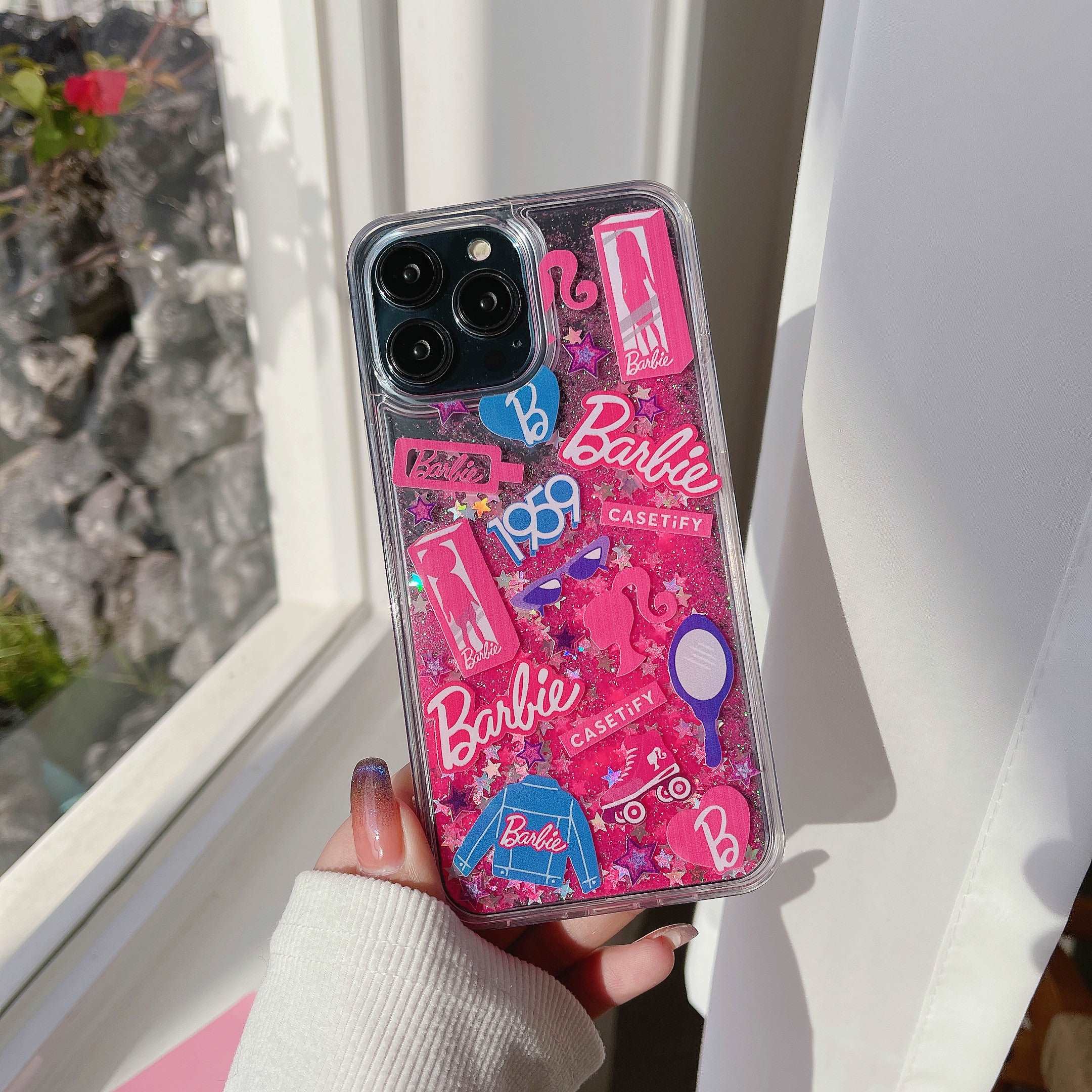 Hand holding a kawaii-style Barbie phone case with pink accents for iPhone