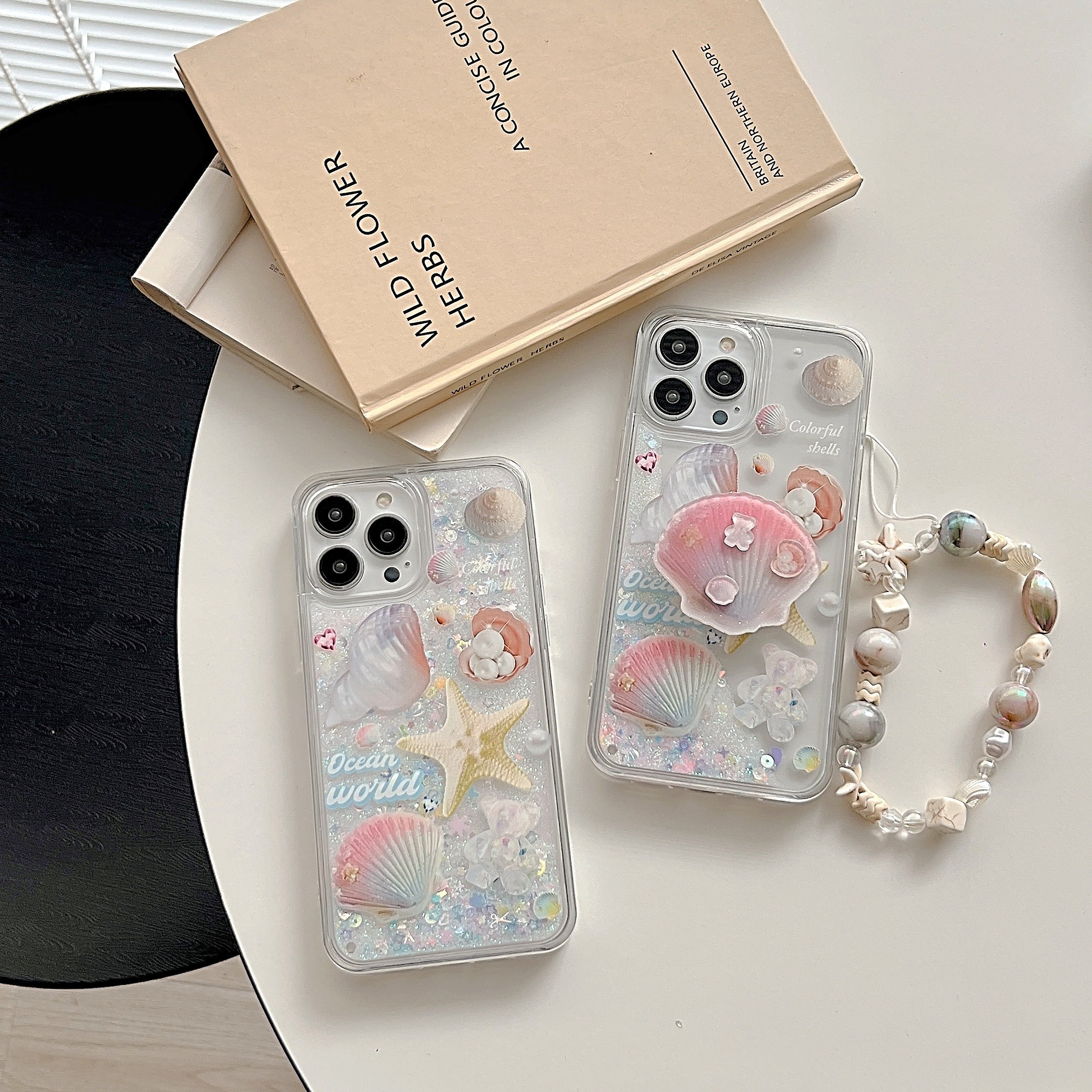 Duo of transparent phone cases from The Little Mermaid series with starfish and shell decorations