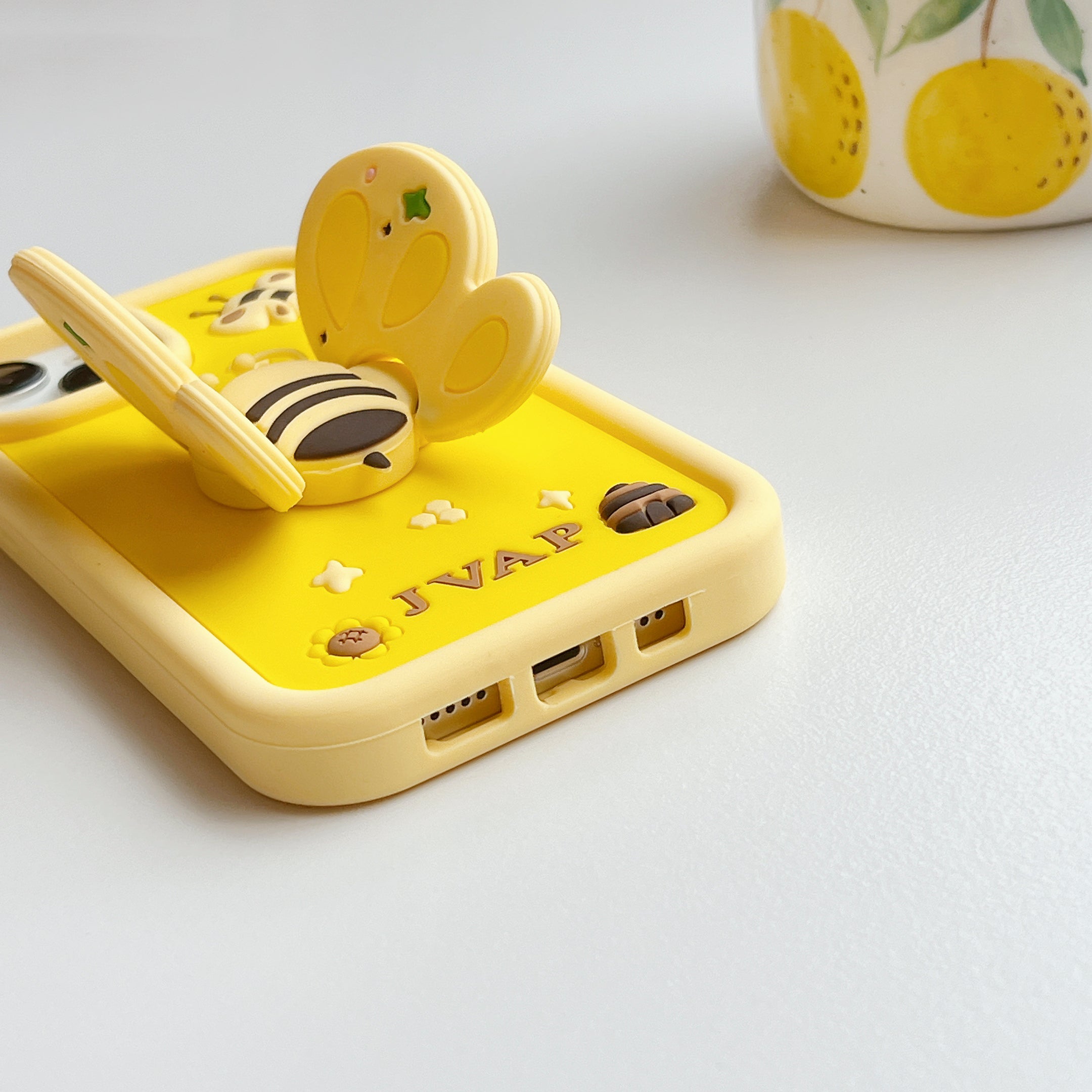 Close-up of a yellow iPhone case with a single bee decoration and shockproof material