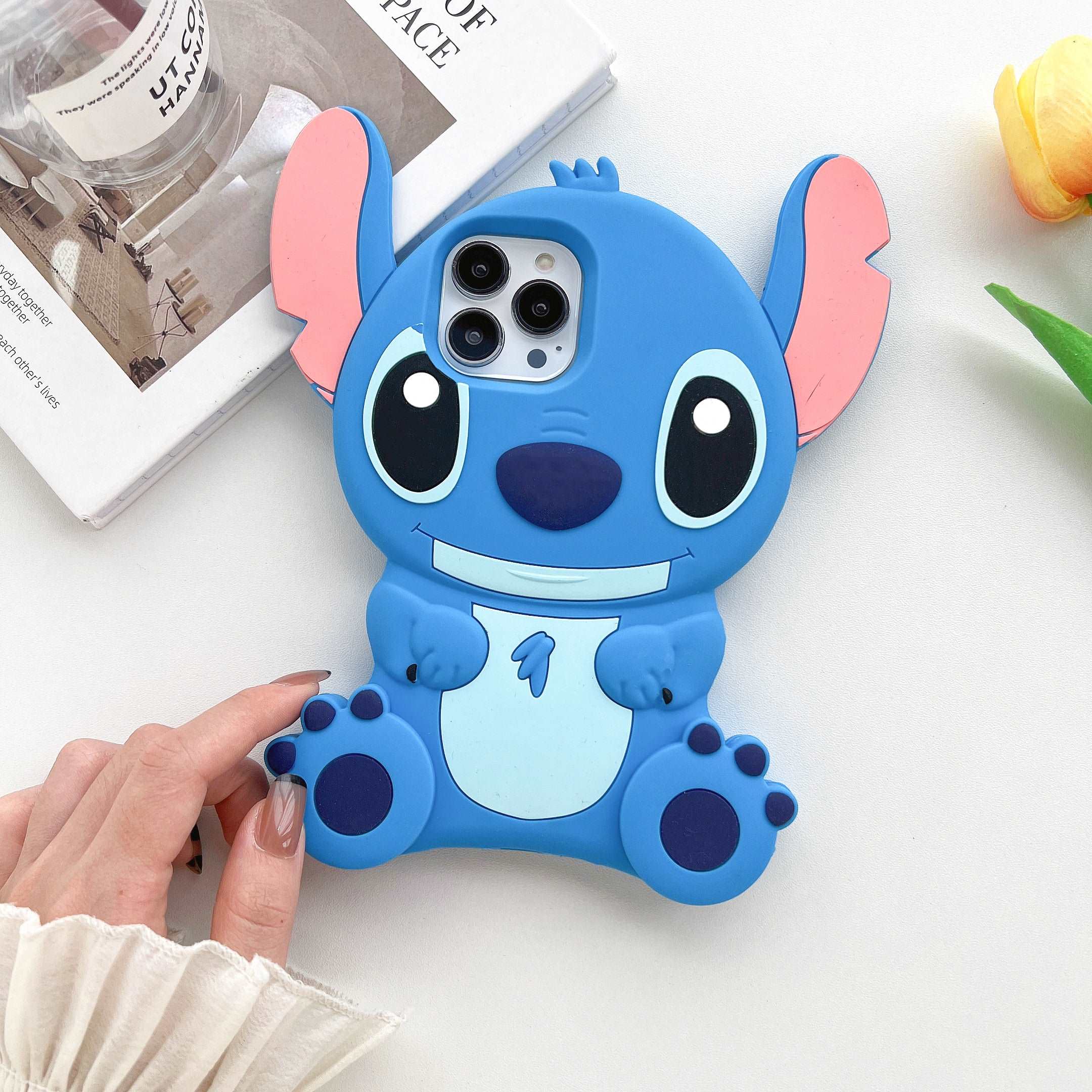 Blue Stitch character silicone case for iPhone 14 held by a person