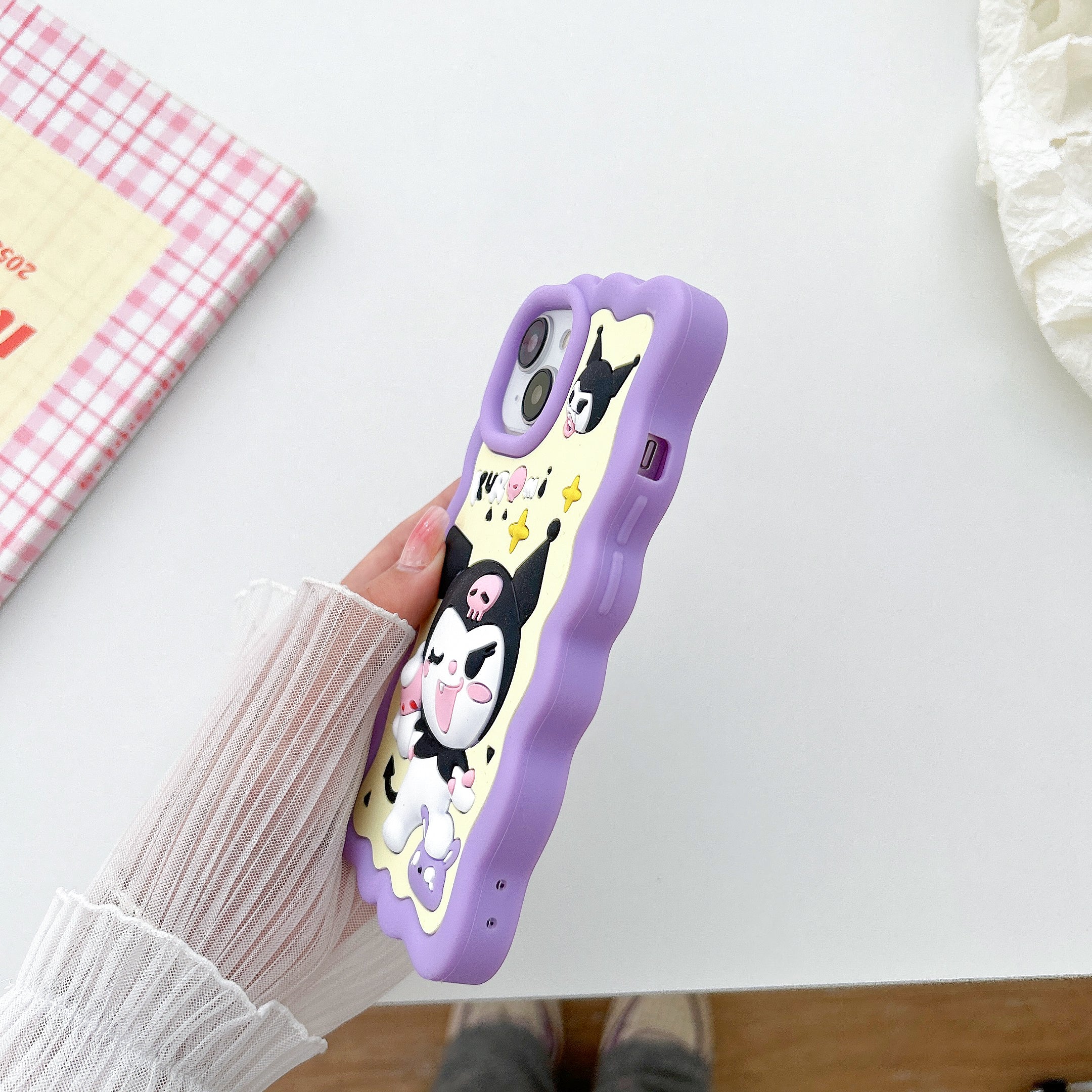 Close-up view of a hand gripping a purple iPhone case with Kuromi motif