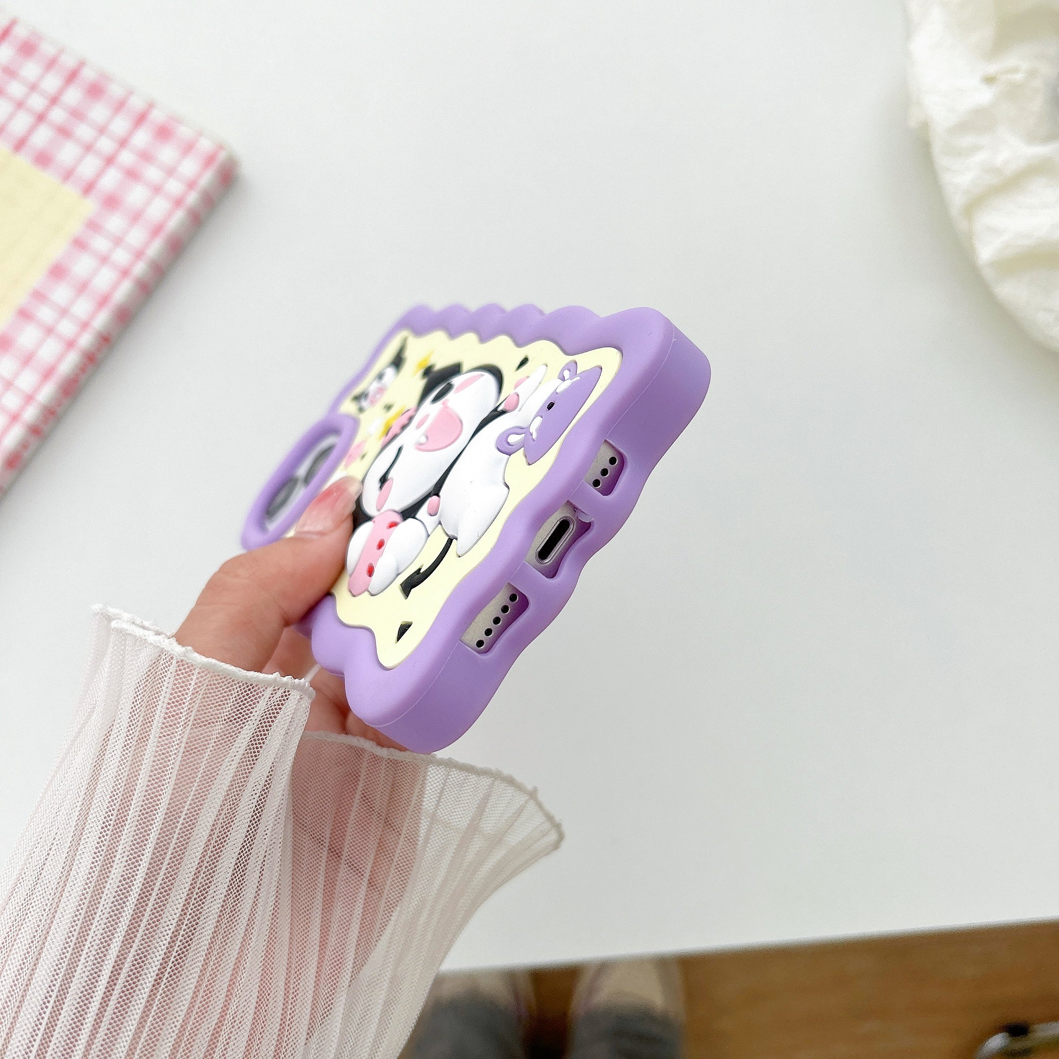 Detailed shot of a hand with a purple iPhone case displaying a Kuromi design